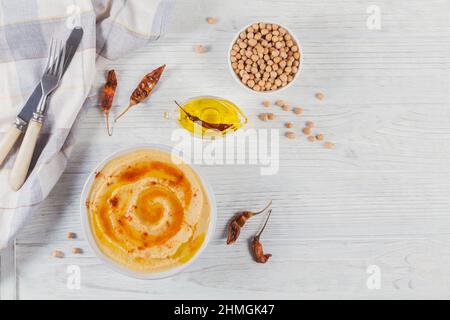 Eine Schüssel mit Kichererbsen hausgemachten Hummus mit Olivenöl und geräuchertem Paprika auf weißem Holzhintergrund. Draufsicht mit Platz Stockfoto