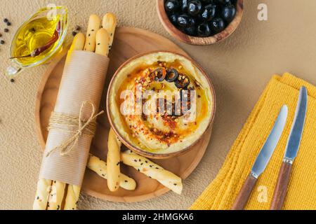 Gesunder hausgemachter cremiger Hummus mit Olivenöl, schwarzen Oliven und Knäckebrot. Gesunde Ernährung und Konzept der Ernährung. Stockfoto