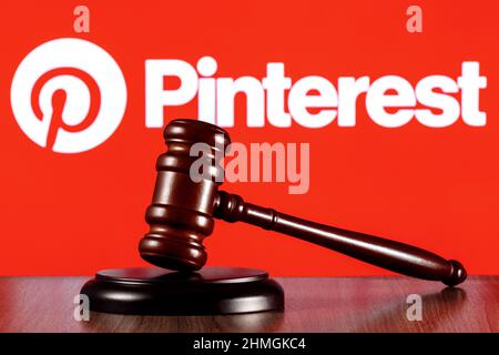 Gavel auf dem Tisch vor dem Hintergrund des Social Media Service-Logos von Pinterest. Das Konzept des Prozesses. Stockfoto