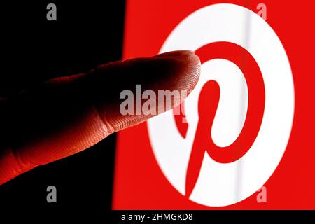 Der Finger greift nach dem Logo des sozialen Mediendienstes von Pinterest auf dem Smartphone-Bildschirm. Stockfoto