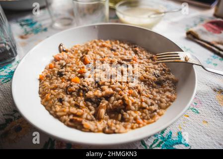 Kürbis und Pilze cremiges Risotto aus der Nähe. Vegetarisches klassisches italienisches hausgemachtes Risotto auf Tischtuch, hausgemachtes Gericht der traditionellen italienischen Küche Stockfoto