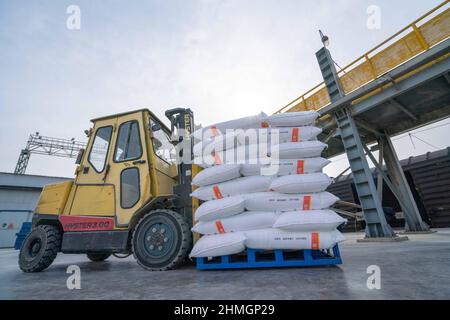 BAZHOU, CHINA - 10. FEBRUAR 2022 - Arbeiter bedienen Gabelstapler, um Dünger in einen Zug in Bozhou, Provinz Xinjiang, China, zu laden, 10. Februar 2022. Stockfoto