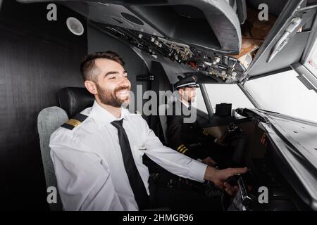 Lächelnder Co-Pilot mit Joch in der Nähe des Kapitäns, während er im Flugsimulator pilotieren Stockfoto