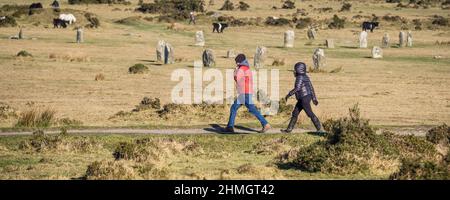 Ein Panoramabild von Menschen, die an den stehenden Steinen, bekannt als die Hurlers Neolithische Steinkreise aus der Bronzezeit, auf den Minion Downs auf Bodmin Moor in vorbeigehen Stockfoto