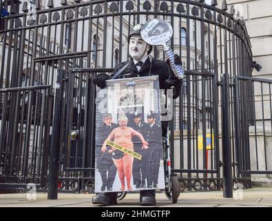 London, Großbritannien. 9th. Februar 2022. Ein Protestler, der als Charlie Chaplin in einer Polizeiuniform vor der Downing Street gekleidet war. Demonstranten versammelten sich in Westminster, als der Druck auf Boris Johnson wegen des Partygate-Skandals weiter ansteigt. Stockfoto