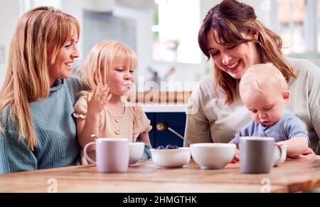 Zwei Mütter Mit Kleinen Kindern Sitzen Am Spieltag Am Tisch Mit Obstsnacks Stockfoto