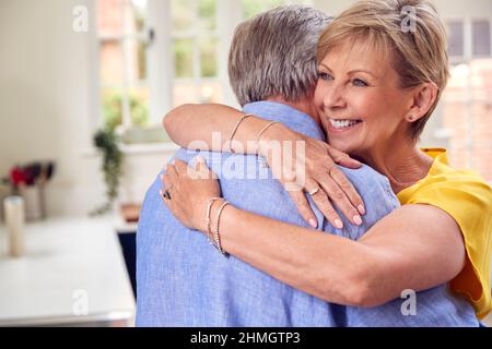 Liebevolles Rentnerpaar Umarmt Sich In Der Küche Zu Hause Zusammen Stockfoto