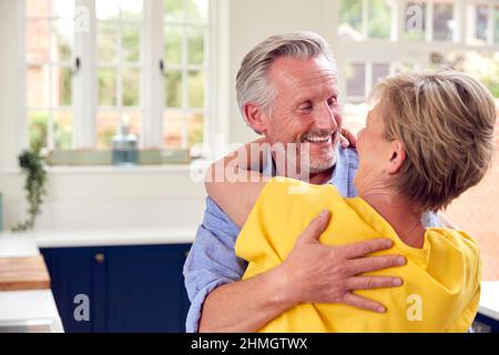 Liebevolles Rentnerpaar Umarmt Sich In Der Küche Zu Hause Zusammen Stockfoto