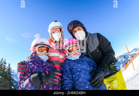 Familie genießt Winterurlaub in Skiausrüstung mit Masken. Familie mit Kindern im Skiurlaub in Skiausrüstung mit Helmen und Ski gog gekleidet Stockfoto