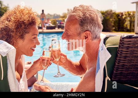 Rentnerpaar Auf Liegestühlen, Entspannung Am Pool Im Sommerurlaub, Champagner Trinken Stockfoto