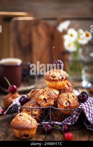 Frische hausgemachte leckere Kirschmuffins auf rustikalem Hintergrund Stockfoto