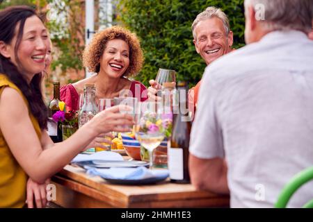 Gruppe Von Reifen Freunden, Die Sich Am Tisch Bei Der Sommerabendessen-Party Im Garten Zu Hause Unterhalten Stockfoto