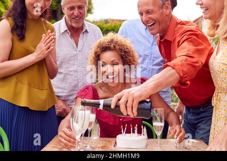 Gruppe Von Reifen Freunden Auf Überraschung Geburtstagsfeier Für Frau Im Garten Mit Kuchen Und Champagner Stockfoto