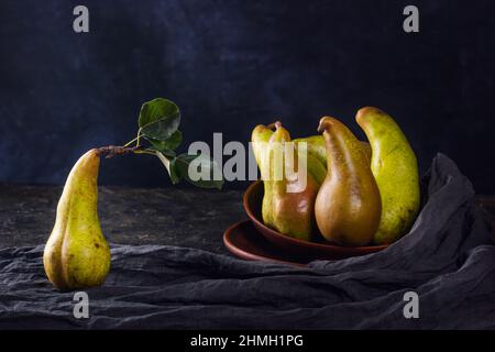 Ländliches Stillleben, dunkle Fotografie mit wenig Ton - Ansicht einer Konferenzbirne in Tontellern, Nahaufnahme mit selektivem Fokus Stockfoto