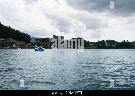 Schwanenboot mit Gebäuden im Hintergrund auf dem Kawaguchi-See in Yamanashi in der Nähe des Fuji-Berges, Japan Stockfoto