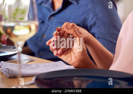 Nahaufnahme Von Multi Generation Family, Die Vor Dem Essen Die Hände Am Tisch Hält Und Grace Sagt Stockfoto