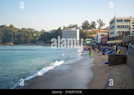 Bild des Strandes in Cheung Chau, Hongkong, mit Sonnenlicht, das während des Sonnenuntergangs auf Gebäude scheint Stockfoto