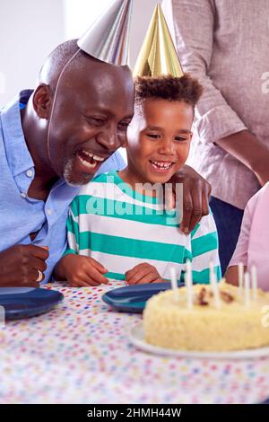 Familie mit mehreren Generationen, die zu Hause um den Tisch sitzt und den Geburtstag des Jungen mit Kuchen und Party feiert Stockfoto