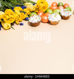 Osterkuchen, Eier und gelbe Tulpen auf beigem Hintergrund mit Platz für Text. Stockfoto