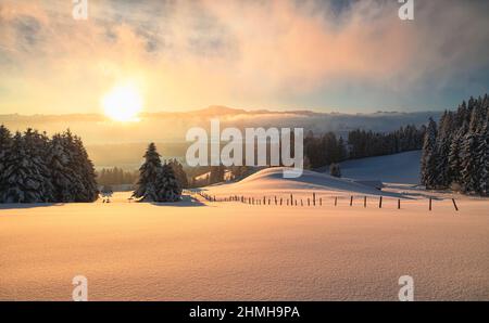 Schöner Sonnenaufgang in einer verschneiten Winterlandschaft. Blick auf das Illertal und die Allgäuer Alpen mit den Grünten. Bayern, Deutschland, Europa Stockfoto