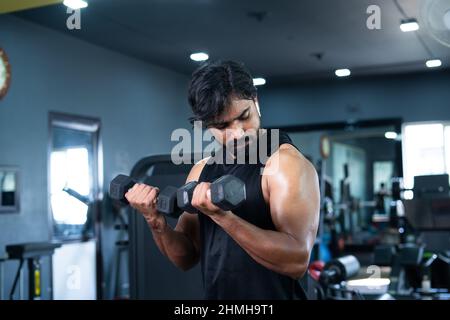 Junge Mann trainieren mit Hanteln für Bizeps im Fitnessstudio - Konzept der Bodybuilding, Fitness-Training-Center, gesunde Lebensweise, Gewichtheben und Stockfoto