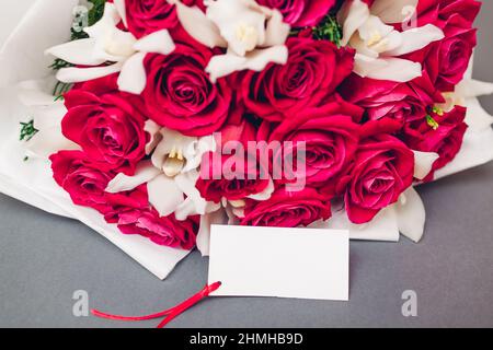 Valentinstag Blumen. Bouquet von roten Rosen und weißen Orchideen mit einer leeren Note. Geschenk für Urlaub. Platz Stockfoto