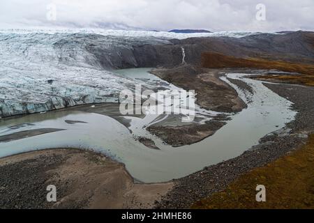 Drohnenaufnahme der Gletscherfront, des Schmelzwassersees, des Schmelzwasserflusses und der herbstlichen arktischen Umgebung des zunehmend dynamisch schmelzenden Russell Glacier im Westen Grönlands mit Blick auf das arktische Hinterland. Stockfoto