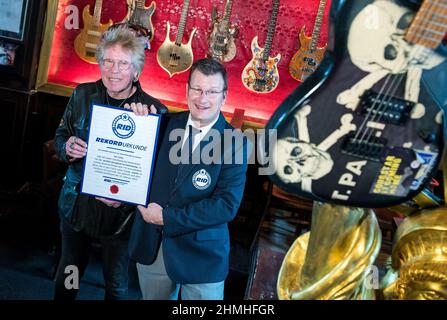 Hamburg, Deutschland. 10th. Februar 2022. Uli Salm (l.), Hamburgs prominenter Moderator und Rockmusiker, erhält von Olaf Kuchenbecker, Rekordrichter des Record Institute for Germany (RID), im Pub Zwick eine Urkunde für seine Bassgitarrensammlung. Salm hat in den letzten 50 Jahren mehr als 700 Bassgitarren gesammelt, und nun hat ihm diese Leidenschaft eine besondere Platte eingebracht. Quelle: Daniel Bockwoldt/dpa/Alamy Live News Stockfoto