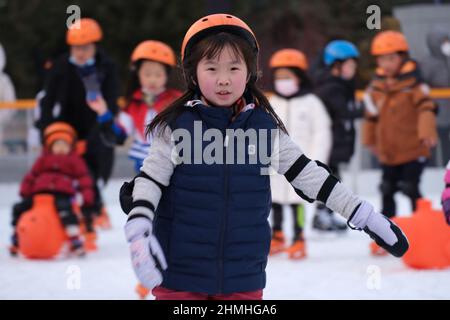 PEKING, CHINA - 10. FEBRUAR 2022 - Kinder üben Schlittschuhlaufen auf einer Eisbahn in Wangfujing, Peking, 10. Februar 2022. Insgesamt 346 Millionen Menschen Stockfoto