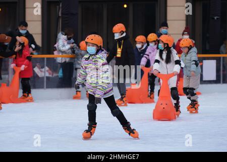 PEKING, CHINA - 10. FEBRUAR 2022 - Kinder üben Schlittschuhlaufen auf einer Eisbahn in Wangfujing, Peking, 10. Februar 2022. Insgesamt 346 Millionen Menschen Stockfoto
