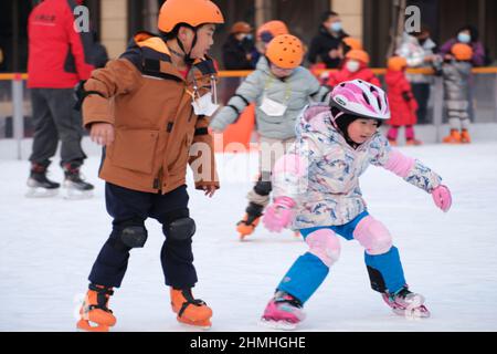 PEKING, CHINA - 10. FEBRUAR 2022 - Kinder üben Schlittschuhlaufen auf einer Eisbahn in Wangfujing, Peking, 10. Februar 2022. Insgesamt 346 Millionen Menschen Stockfoto