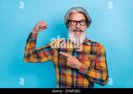 Foto von reifen Mann Punkt Finger Arm Muskeln Anzeige empfehlen Promo sportliche Blink Auge isoliert über blauen Hintergrund Stockfoto