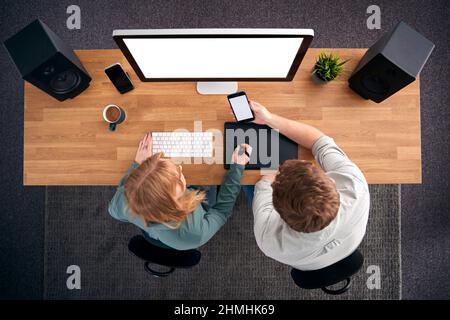 Overhead-Ansicht Von Grafikdesignern, Die Am Computer Arbeiten, Mit Blick Auf Das Mobiltelefon Stockfoto