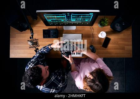 Overhead-Ansicht Von Männlichen Und Weiblichen Musikern Am Arbeitsplatz Mit Tastatur Und Mikrofon Im Studio Stockfoto