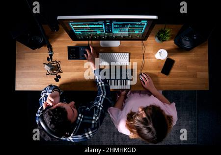 Overhead-Ansicht Von Männlichen Und Weiblichen Musikern Am Arbeitsplatz Mit Tastatur Und Mikrofon Im Studio Stockfoto