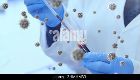Bild von schwimmenden Makrozellen Covid-19 über dem Arzt, der eine Probe nimmt und medizinische Handschuhe trägt Stockfoto