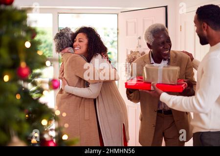 Erwachsene Kinder Grüße An Ältere Eltern, Die Mit Geschenken Zur Feier Von Weihnachten Ankommen Stockfoto
