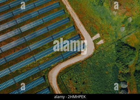 Blick aus der Vogelperspektive auf Reihen von Solarmodulen mit einer Zufahrtsstraße zum Turrill Solar Plant, das Haushalte in Lapeer, Michigan, USA, mit erneuerbarer Energie versorgt Stockfoto