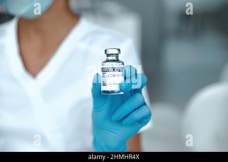 COVID-19-Impfstoff in Forscherhand hält Ärztin Spritze und Flasche mit Impfstoff für die Coronavirus-Heilung. Stockfoto
