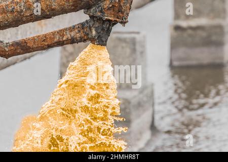 Verschmutzter Wasserkopf, der aus einer alten rostigen Rohrleitung austritt. Stockfoto