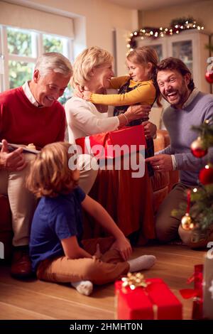 Multi-Generation-Familie Austausch Und Eröffnung Geschenke Rund Um Weihnachtsbaum Zu Hause Stockfoto