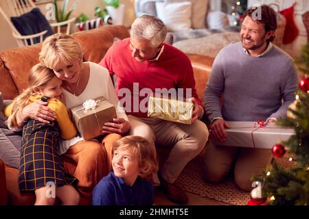 Multi-Generation-Familie Austausch Und Eröffnung Geschenke Rund Um Weihnachtsbaum Zu Hause Stockfoto