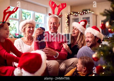 Multi-Generation-Familie Austausch Und Eröffnung Geschenke Rund Um Weihnachtsbaum Zu Hause Stockfoto