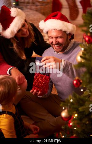 Vater Mit Geschenk Von Socken Als Multi-Generation-Familie Opening Geschenke Rund Um Weihnachtsbaum Stockfoto