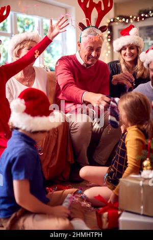 Multi-Generation-Familie Austausch Und Eröffnung Geschenke Rund Um Weihnachtsbaum Zu Hause Stockfoto