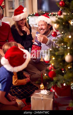 Multi-Generation-Familie Austausch Und Eröffnung Geschenke Rund Um Weihnachtsbaum Zu Hause Stockfoto