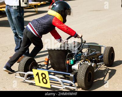 ODESSA, UKRAINE - 2. APRIL 2017: Wettkämpfe auf dem Bild, Piloten in Helm und Rennkleidung nehmen am Kartenrennen Teil. Kart-Show. Kind Stockfoto