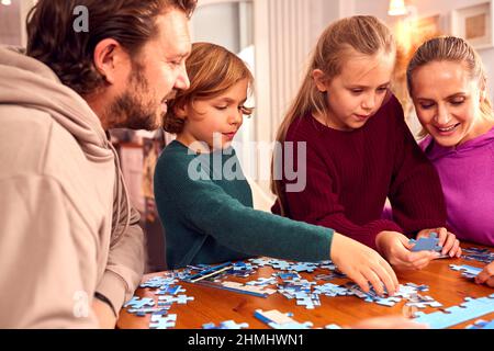Familie Sitzt Um Den Tisch Zu Hause Tun Puzzle Zusammen Stockfoto