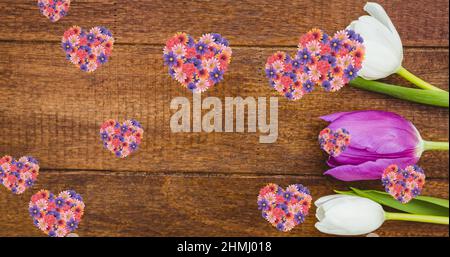 Bild von Herzen von bunten Blumen schweben über Holzoberfläche mit weißen und rosa Tulpen Stockfoto