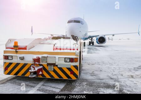 Der Schlepper schiebt das Passagierflugzeug im kalten Winter flughafenvorfeld Stockfoto